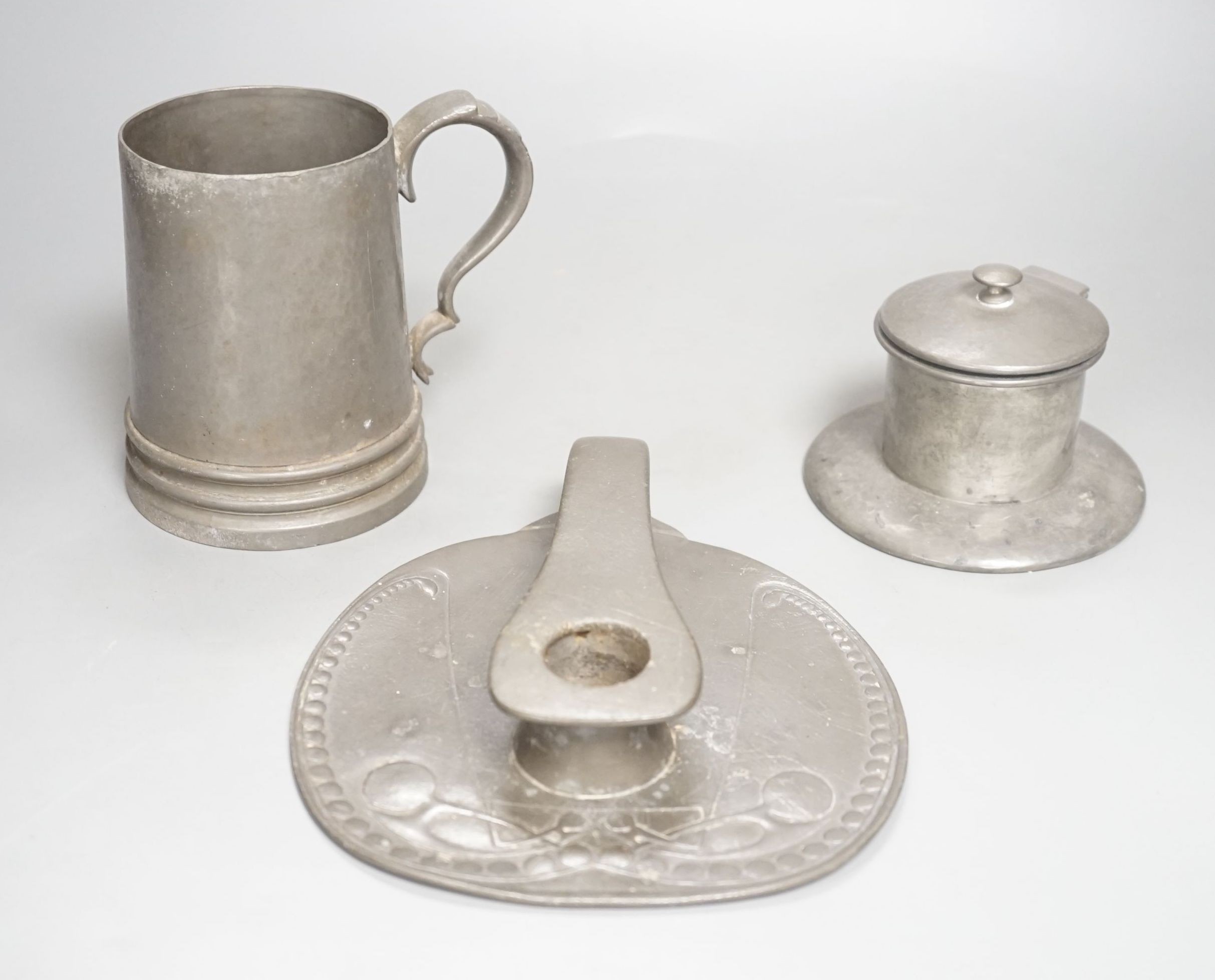 A Liberty Tudric pewter chamberstick, inkwell and mug. Length of chamberstick 18cm, model numbers 0523, 01135, and 01352